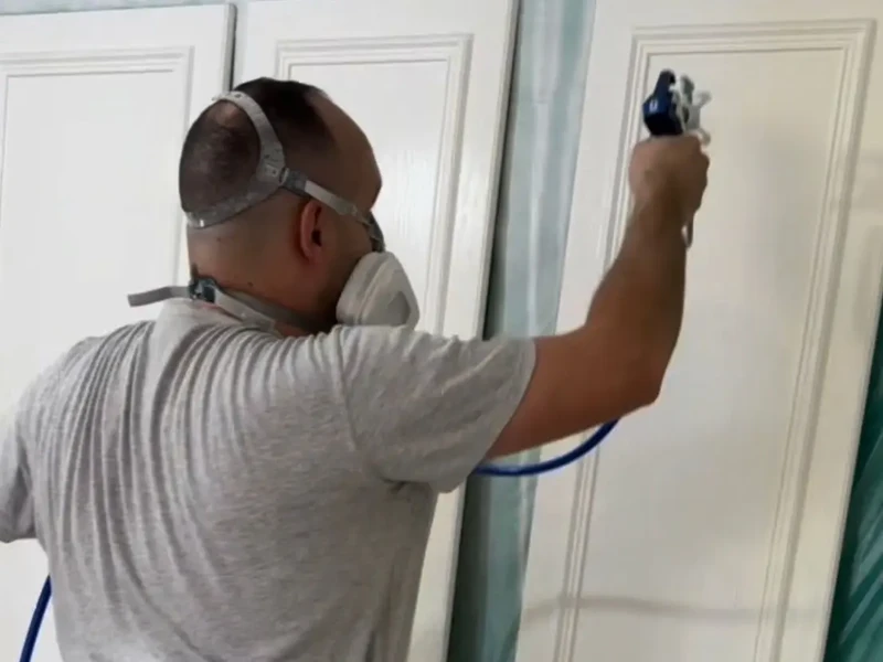 Martin Cole spray painting white fitted furniture doors